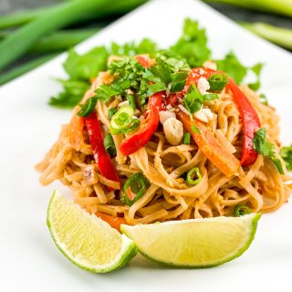 a plate of vegetable pad thai with limes